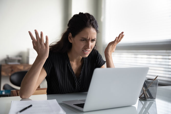 Woman throwing her hands in the air out of frustration with managing her website.

